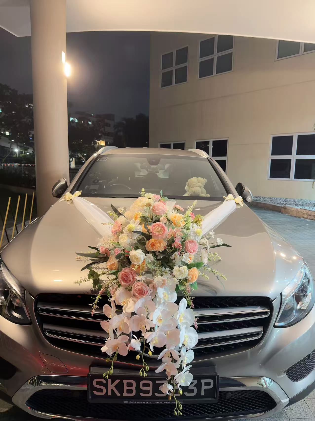 Front view of silver bridal car featuring cascading white orchids and pastel roses